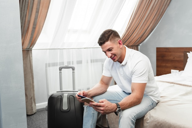 Homem usando smartphone no quarto de hotel