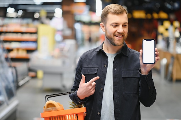 Homem usando Smartphone no supermercado