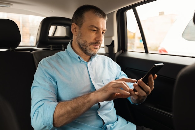 Foto homem usando smartphone sentado no banco do passageiro do carro