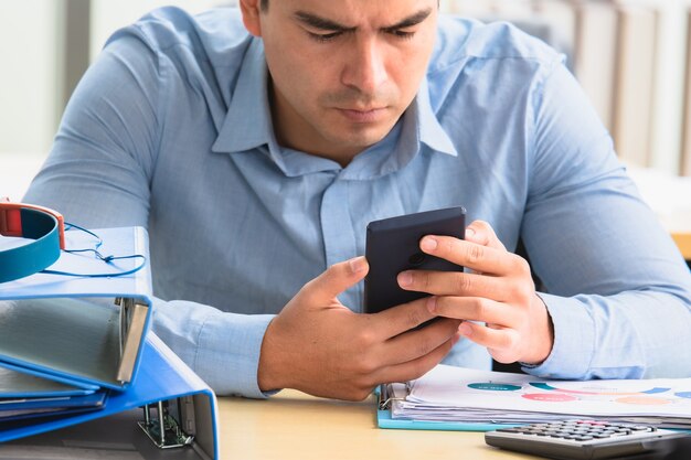 Homem usando smartphone sentado no escritório, tecnologia de internet online