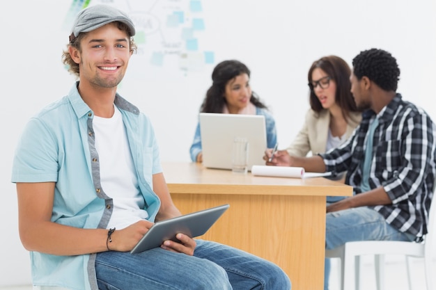 Homem usando tablet digital com colegas atrás no escritório