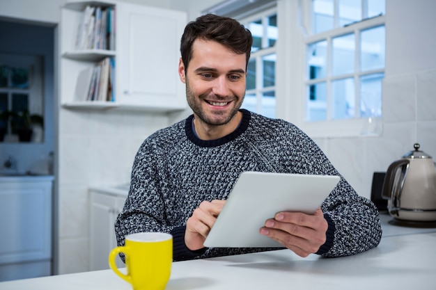 Homem usando tablet digital na cozinha