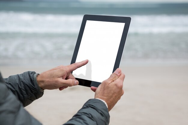 Homem usando tablet digital na praia