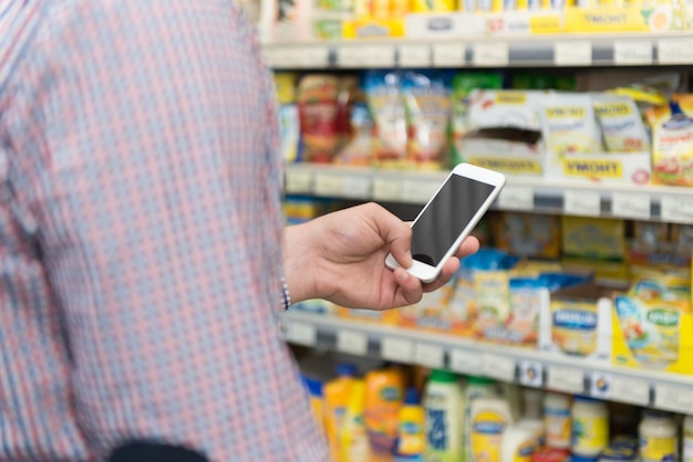 Homem usando telefone celular closeup enquanto fazia compras na loja de compras