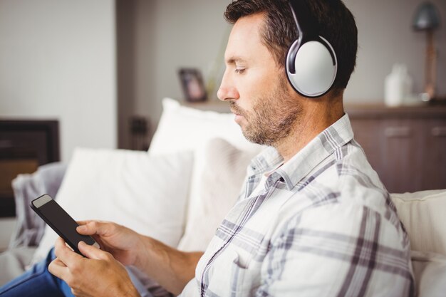 Homem usando telefone celular enquanto usava fones de ouvido