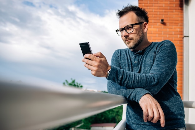 Foto homem usando telefone no terraço