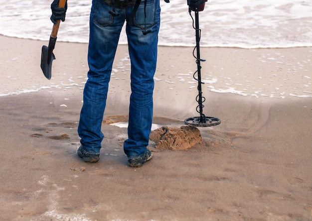 Homem usando um detector de metais para procurar metais ou tesouros perdidos na praia