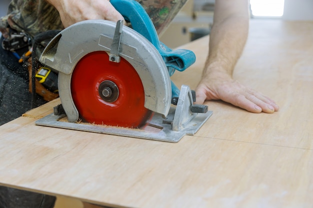 Homem usando uma serra circular para cortar madeira compensada na fábrica de produção de madeira