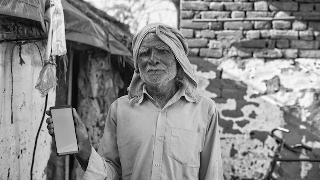 Foto homem velho asiático sorrindo e mostrando um telefone celular de tela verde com o conceito de fundo da vida da aldeia rural