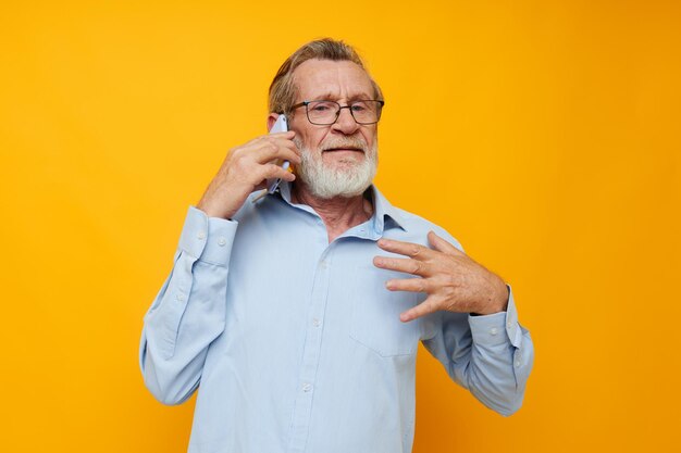 Homem velho com telefone posando em fundo amarelo