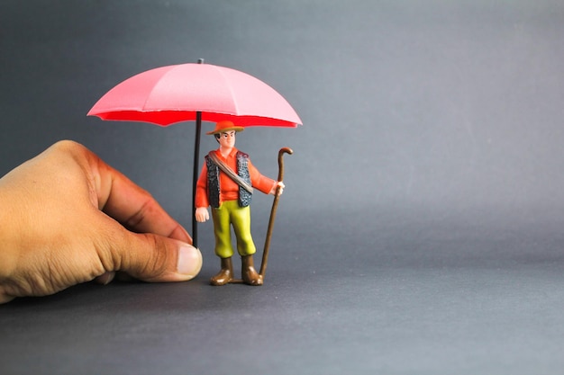 homem velho em miniatura com guarda-chuva o conceito de proteção na velhice conceito de proteção de seguro