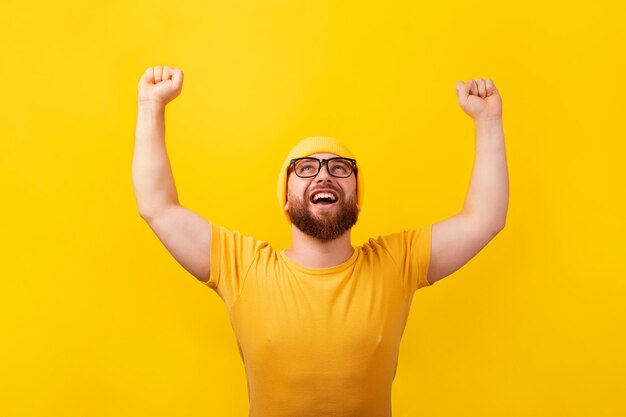 Homem vencedor feliz olhando para cima sobre fundo amarelo