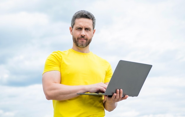 Homem verifica e-mail no laptop no fundo do céu