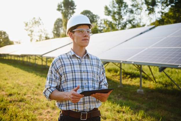 Homem verificando e parado perto de painéis solares