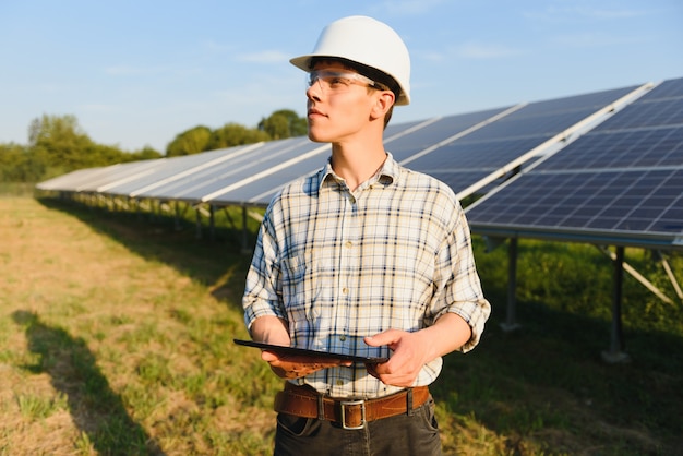 Homem verificando e parado perto de painéis solares