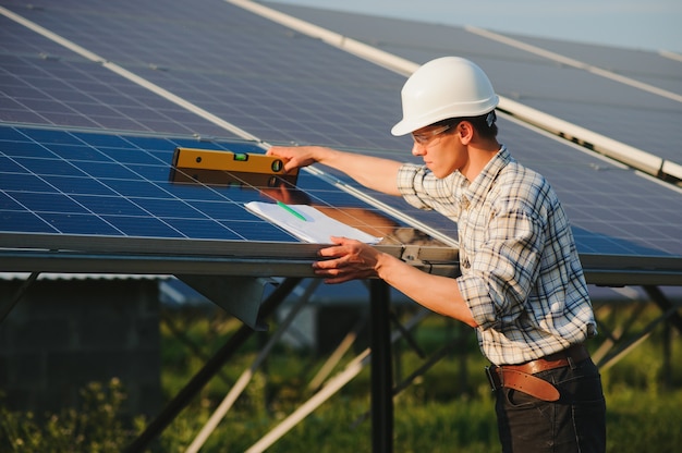 Homem verificando e parado perto de painéis solares