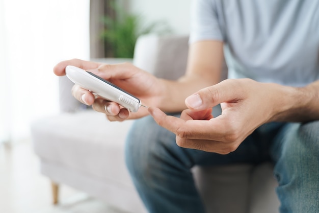 Homem verificando o nível de açúcar no sangue pelo medidor digital de glicose, saúde e medicina, conceito de diabetes