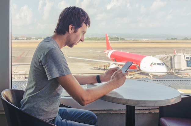 Homem verificando seu telefone no aeroporto