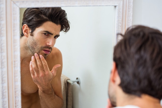 Homem verificando sua barba por fazer no banheiro