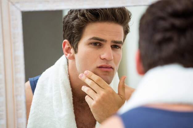 Homem verificando sua barba por fazer no banheiro