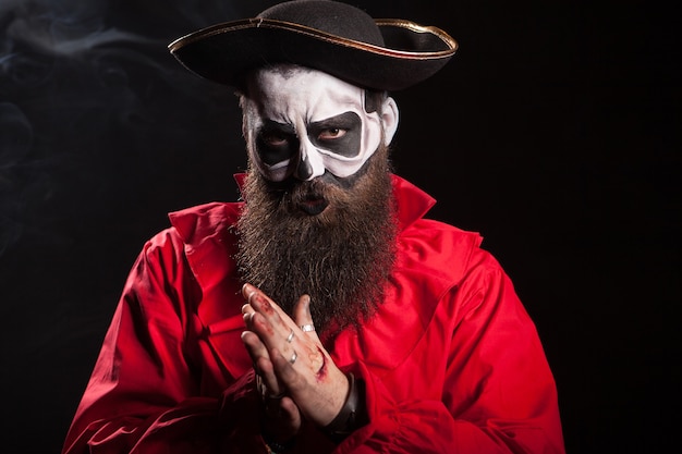 Homem vestido como um pirata assustador para a celebração do halloween sobre fundo preto.