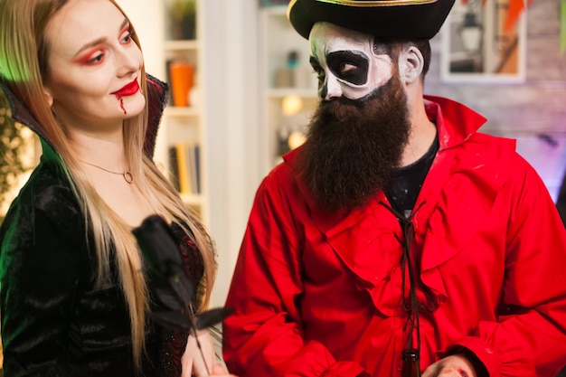 Homem vestido como um pirata tentando seduzir uma mulher vampira na festa de halloween.