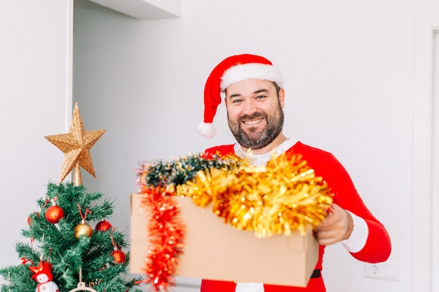 Homem vestido de Papai Noel decorando a árvore de Natal