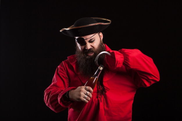 Homem vestido de pirata para o halloween, abrindo uma garrafa com o gancho. homem com chapéu de pirata. homem com roupas de pirata.