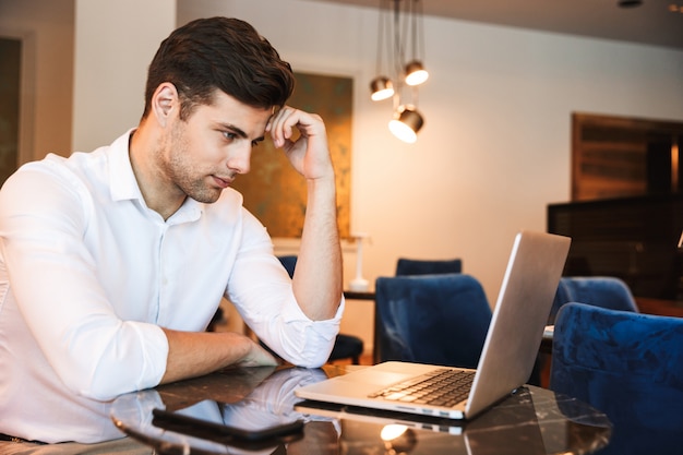 Homem vestido formal jovem pensativo trabalhando no laptop