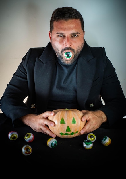 Homem vestido para o halloween com uma abóbora na mão.