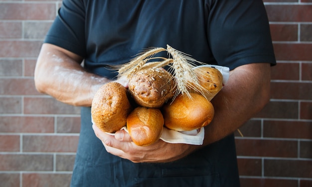 Foto homem vestindo avental segurando pão recém-assado