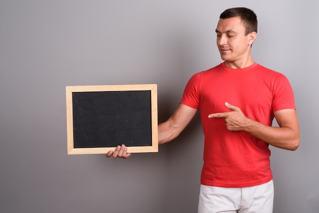 Homem vestindo camisa vermelha contra parede cinza