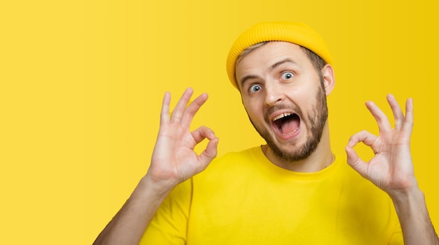 Foto homem vestindo camiseta amarela sobre fundo amarelo isolado e fazendo sinal okey pelos dedos