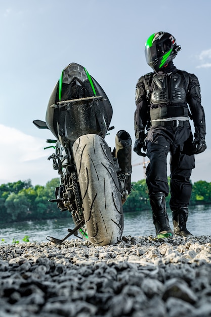 Homem vestindo capacete de motocicleta e uniforme de segurança, sentado na bicicleta ao ar livre, bela paisagem cênica