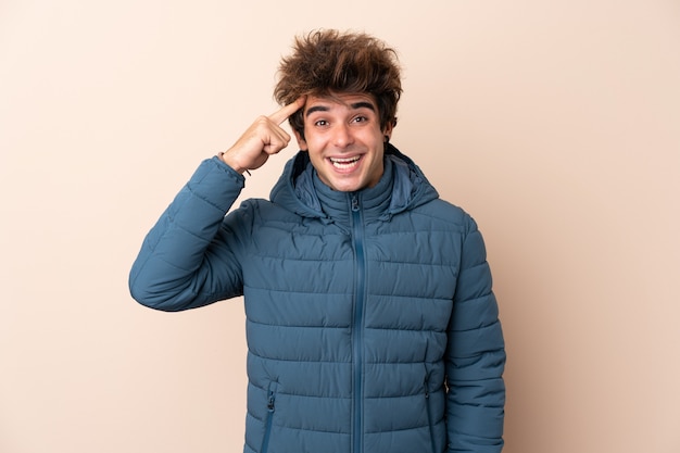 Foto homem vestindo jaqueta de inverno sobre parede isolada, com a intenção de perceber a solução