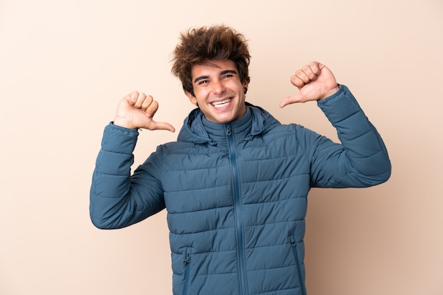 Foto homem vestindo jaqueta de inverno sobre parede isolada, orgulhoso e satisfeito