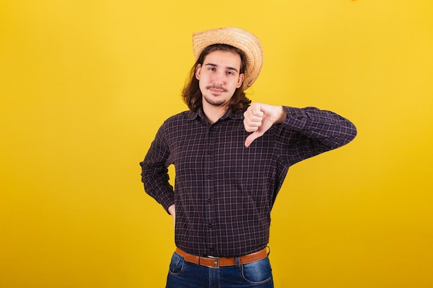 Homem vestindo roupas típicas para festa Junina Polegar para baixo reprovado desaprovação negativa