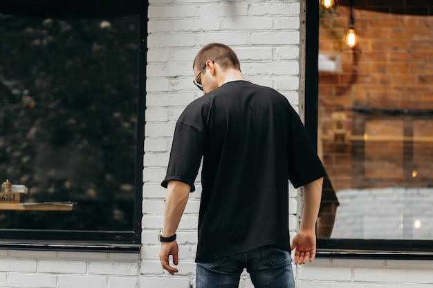 Homem vestindo uma camiseta preta em branco com espaço para seu logotipo ou desenho. Simulação