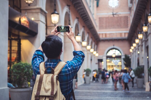 Foto homem viagem conceito turista tirando foto por telefone e colocar mão sobrecarga para atirar rua e cidade