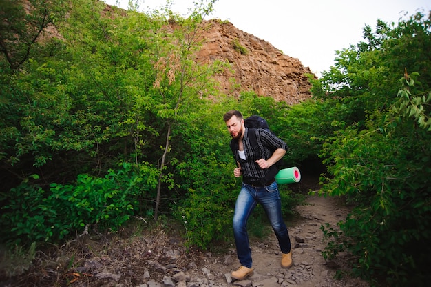 Foto homem viajante andando com mochila nas montanhas rochosas.