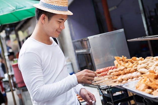 homem viajante apreciando comida de rua asiática Tailândia