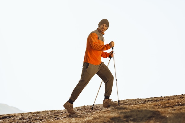 Homem viajante com bastões de trekking subindo a montanha