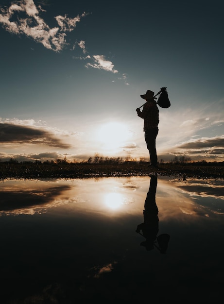Homem viajante de pé e olhando para o pôr do sol Belo reflexo na água