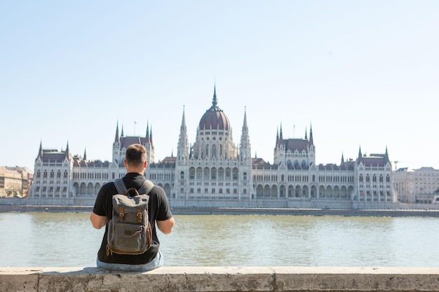 Homem viajante em frente ao edifício do parlamento de Budapeste