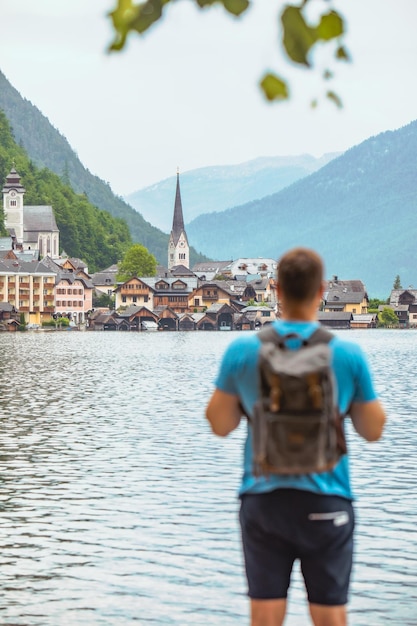 Homem viajante mochileiro olhando para a cidade de hallstatt do outro lado do lago