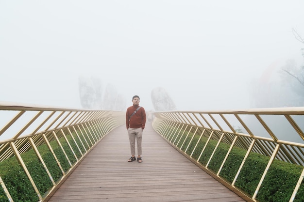 Homem Viajante passeando Ponte dourada no topo do marco de Ba Na Hills e popular conceito de viagem para o Vietnã e Sudeste Asiático