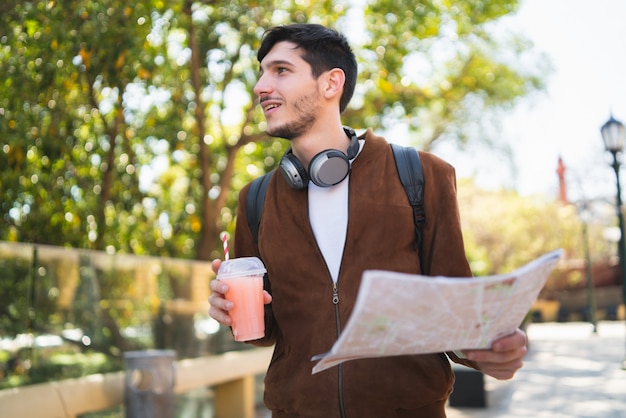 Homem viajante segurando um mapa e procurando instruções.