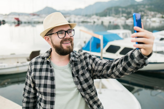 Homem viajante tirando selfie de iates de luxo marinhos durante viagens de dia ensolarado e conceito de verão