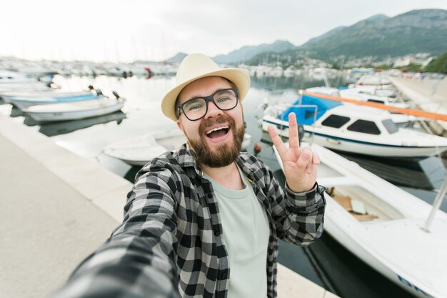 Homem viajante tirando selfie de iates de luxo marinhos durante viagens de dia ensolarado e conceito de verão