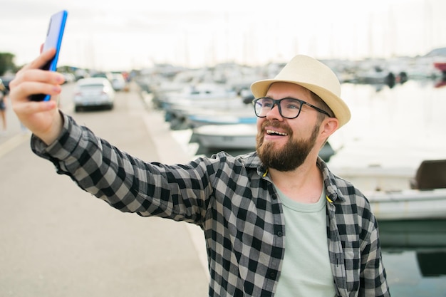 Homem viajante tirando selfie de iates de luxo marinhos durante viagens de dia ensolarado e conceito de verão
